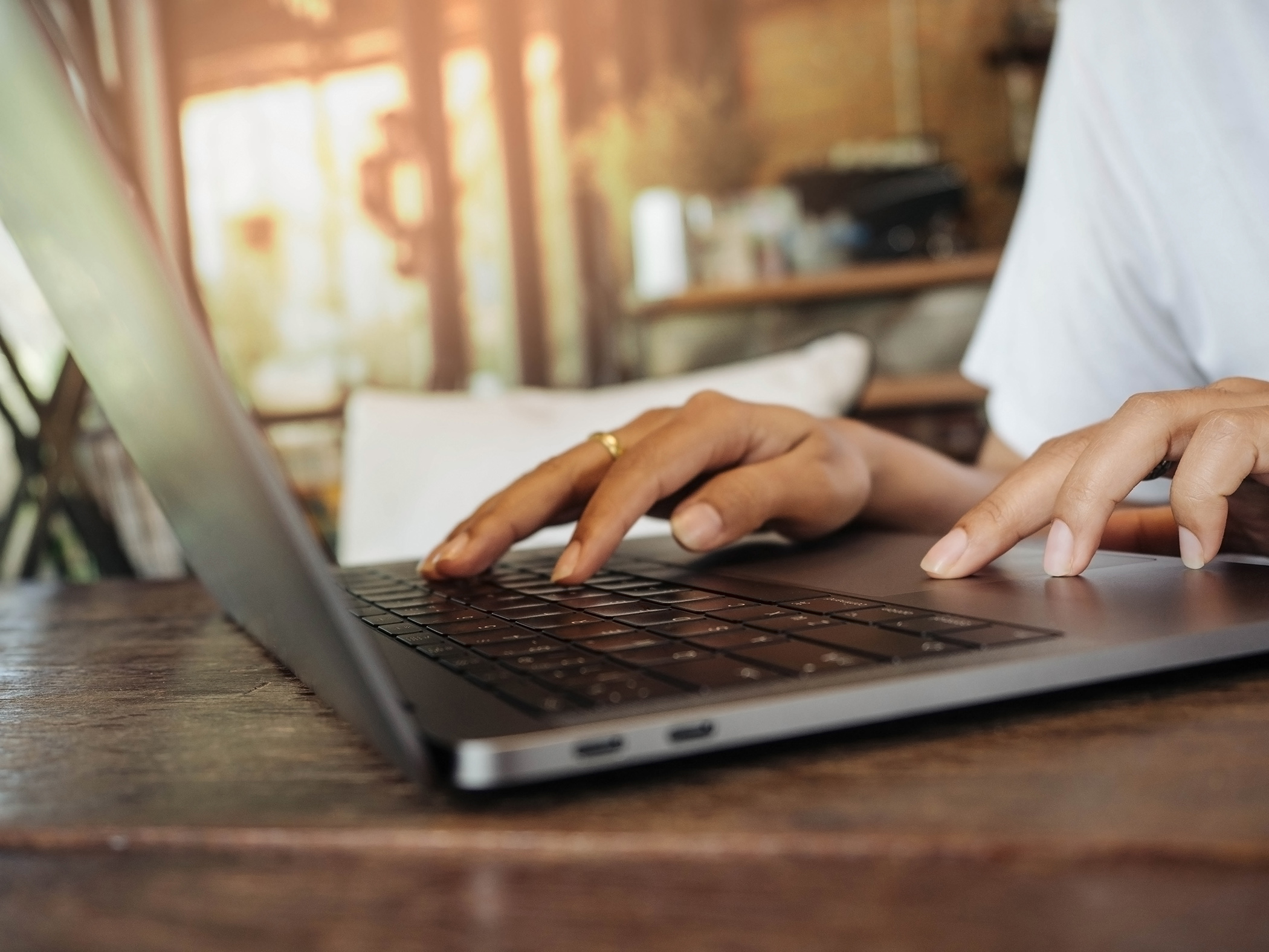 Closeup of women's hand is business working by touching laptop keyboard on wood table in coffee cafe